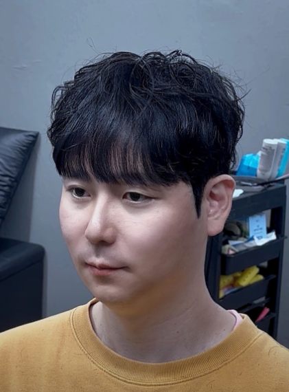 시스루 쉐도우펌 시술 사진 — 부스스한 컬로 윗머리 볼륨을 살린 남자 펌